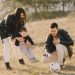 A happy family playing with a soccer ball in a grassy field on a sunny day.
